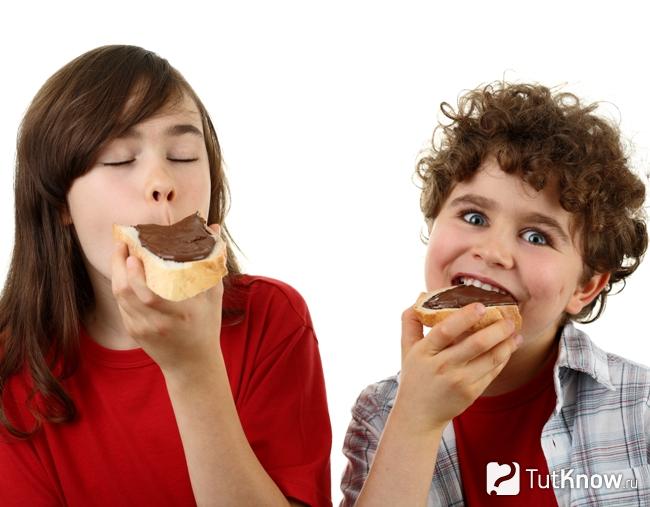 Дети едят бутерброд с шоколадным маслом