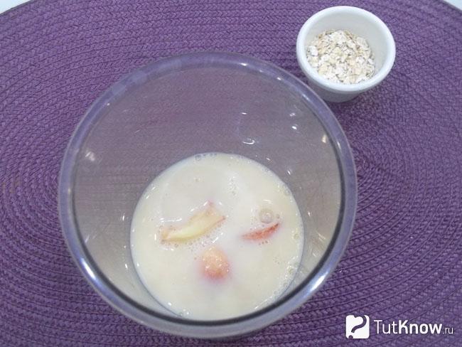 Персики сложены в чашу блендера и залиты молоком