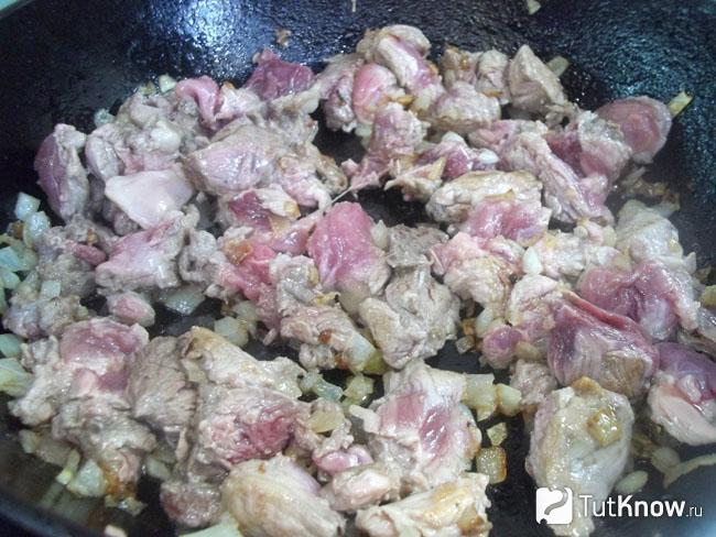 Мясо с луком жарится на сковороде