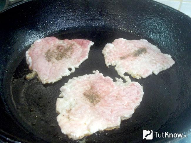 Мясо приправлено перцем и жарится в сковороде
