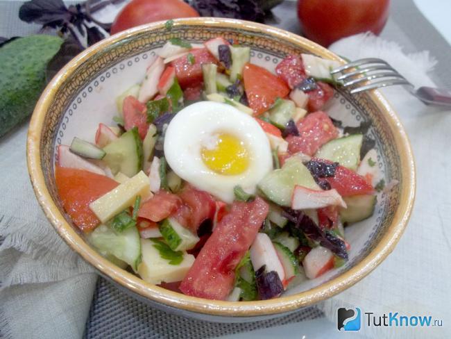 Готовый салат с крабовыми палочками, помидорами, сыром и яйцом-пашот