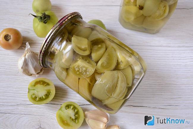 Банка с зелеными маринованными помидорами вид сверху