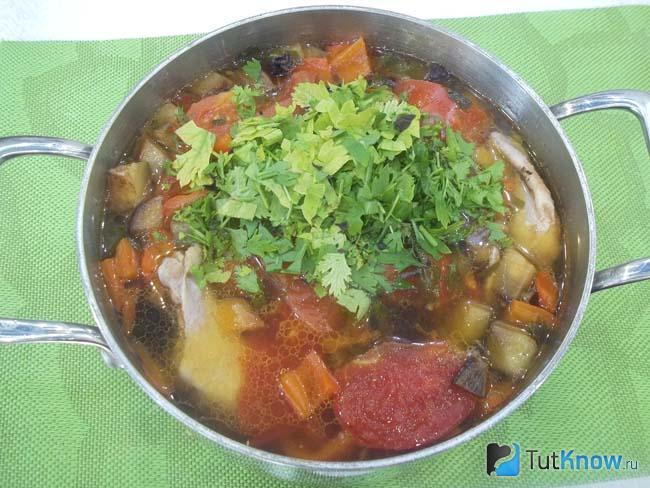 Готовый жареный овощной суп с курицей приправлен зеленью