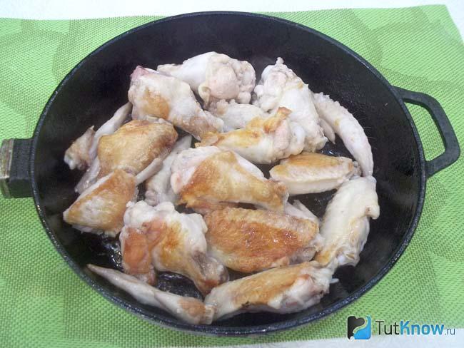 Куриные крылышки нарезаны по фалангам и жарятся в сковороде
