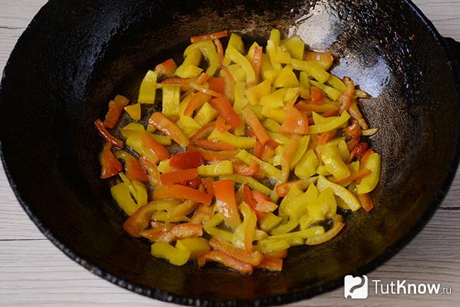 Нарезанный полосками лук и сладкий перец на сковородке