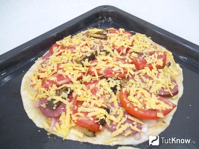 Продукты присыпаны сыром и пицца отправлена в духовку