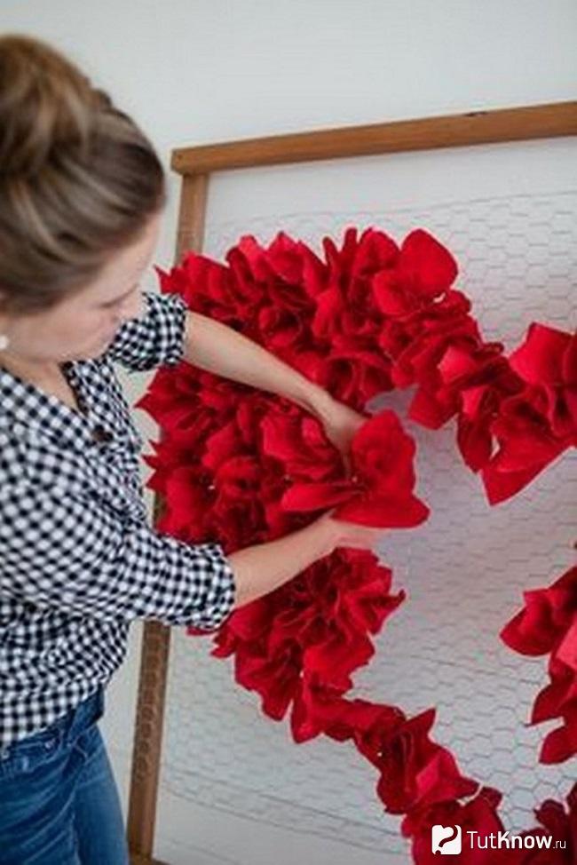 Девушка собирает цветок из красной бумаги