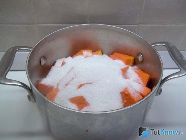 Тыква сложена в кастрюлю и засыпана сахаром