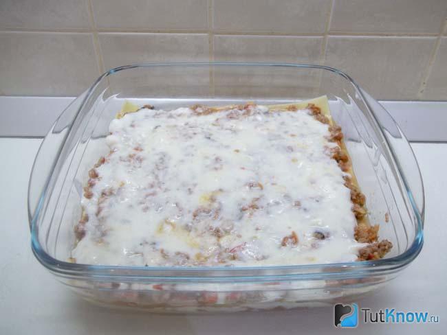На листы лазани выложены соусы болоньезе и бешамель