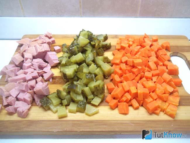 Морковь, огурцы и колбаса нарезаны кубиками
