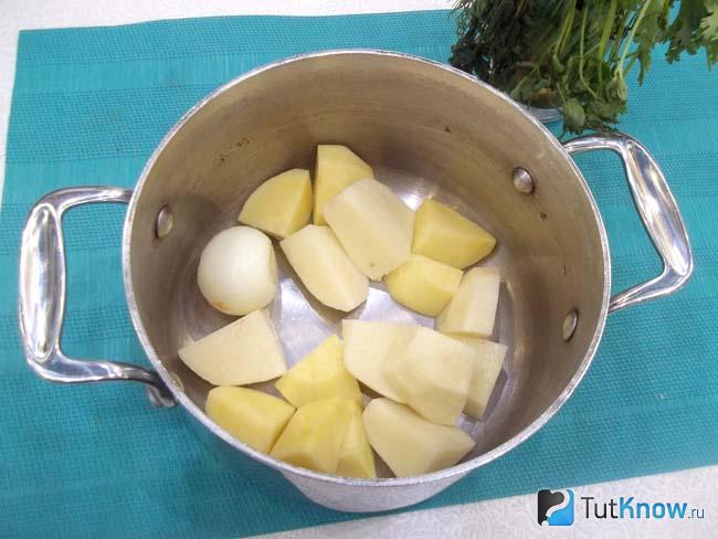 В кастрюлю сложен картофель с луком