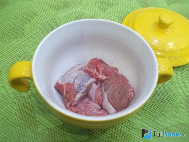 Мясо нарезано и сложено в горшочек