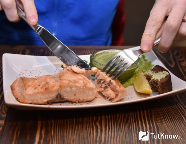 Мужчина ест мясо с зеленым соусом