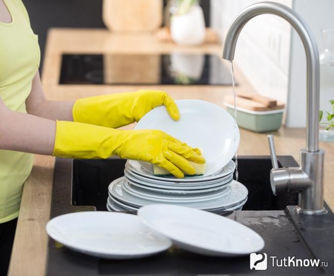 Мытье посуды в защитных перчатках для предотвращения сухости кожи рук