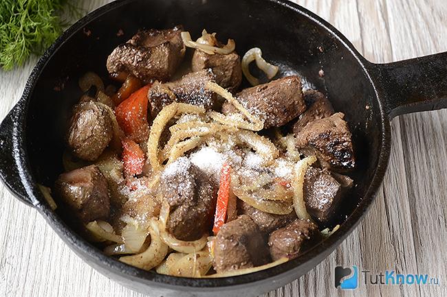 Печень с овощами на сковороде посыпана сахаром