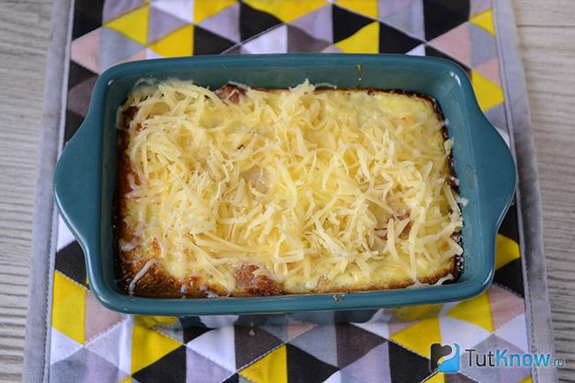Готовая мясная запеканка с цветной капустой, украшенная тертым сыром