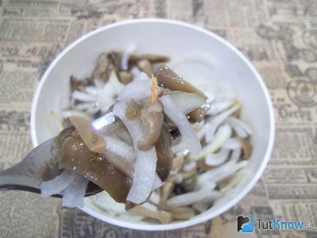 Готовый салат с маринованными грибами, луком и маслом