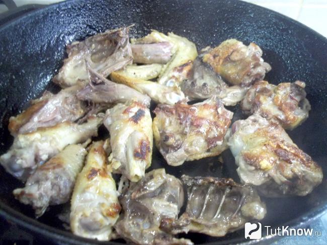 Петух жарится в сковороде до румяной корочки