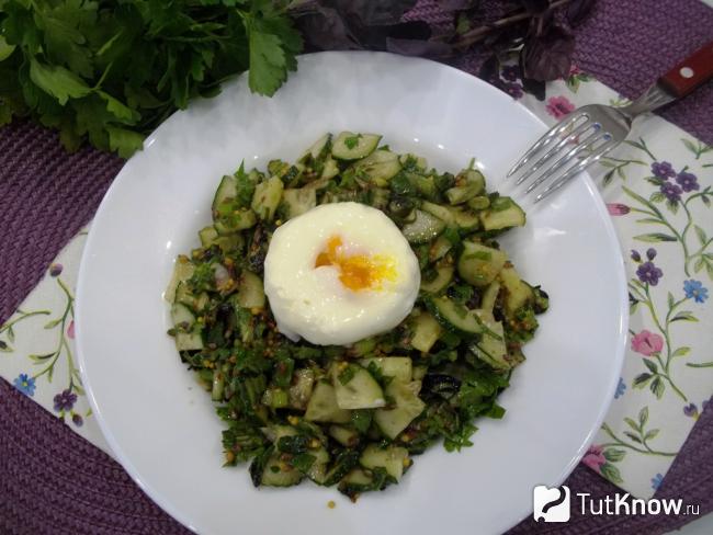 Готовый салат с огурцами, зеленью, семенами льна и яйцом-пашот