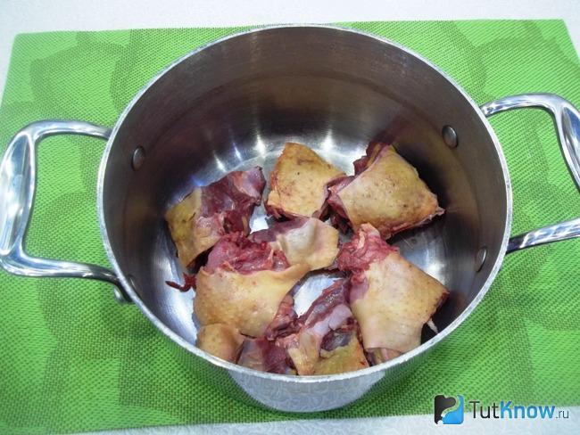 Утка нарезана кусочками и сложена в кастрюлю