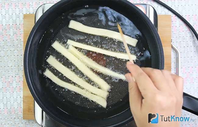 Картофельные палочки жарятся на сковороде в масле