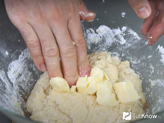 Сливочное масло нарежьте кусочками и добавьте в тесто