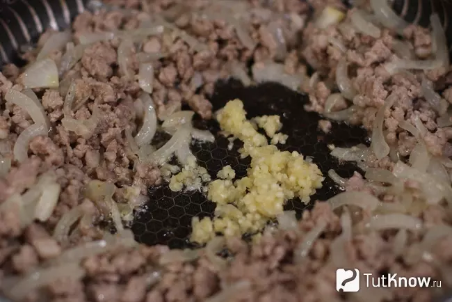 Фарш с мягким луком и добавленным измельчённым чесноком в центре сковороды