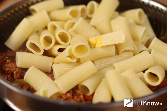Отваренная паста ригатони и кусочек сливочного масла, добавленные к мясному соусу