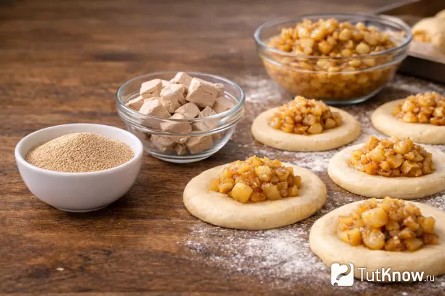 Сухие и прессованные дрожжи рядом с формовкой булочек с яблоками