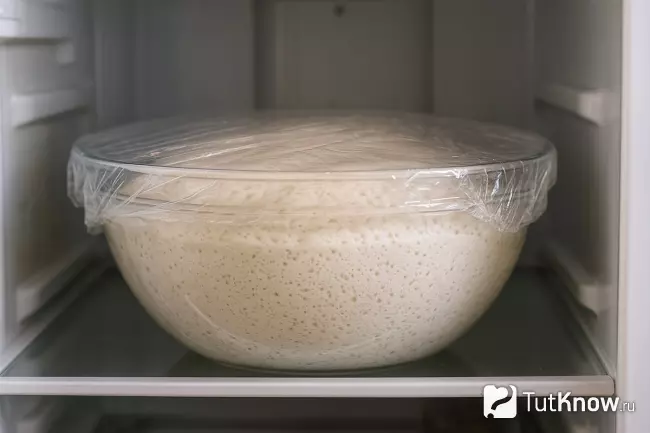 Тесто поднимается в миске в холодильнике под плёнкой