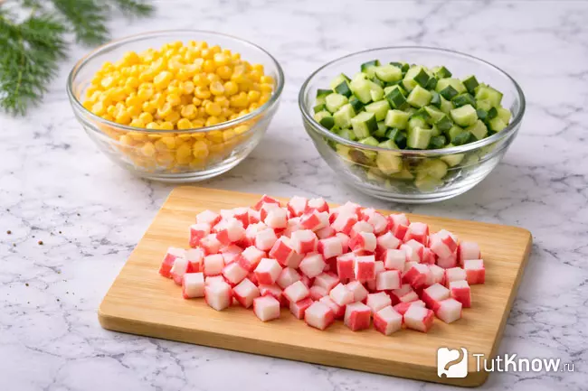 Шаг 2 - нарезанные кубиком крабовые палочки, огурец и кукуруза