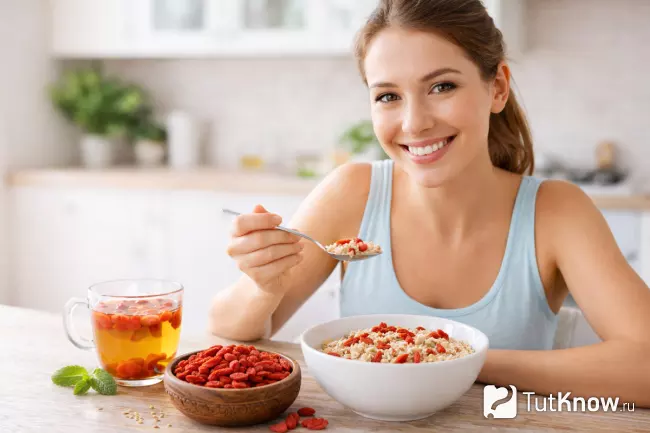 Девушка кушает овсяную кашу с ягодами годжи