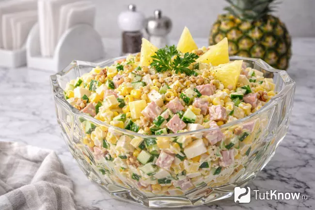 Салат с ананасом, ветчиной и огурцом в стеклянной салатнице