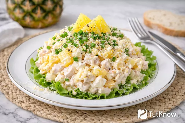 Красивая подача салата с ананасом и яйцом на тарелке на листе салата