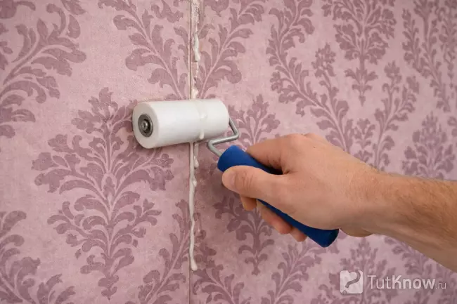 Разглаживание стыка обоев валиком от центра