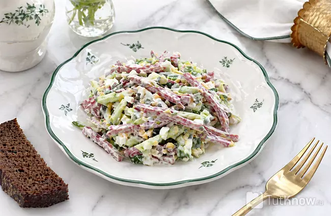 Готовый салат с копченой колбасой, сыром, яйцом и огурцом