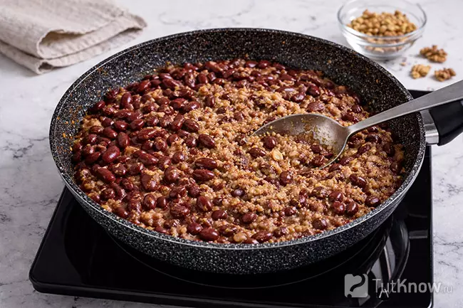 Смешивание фасоли с зажаркой и разминание для лобио